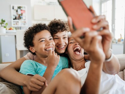 Zahnspange für Kinder & Erwachsene über die Zahnzusatzversicherung: Kinder mit Zahnspangen albern mit einem Smartphone herum