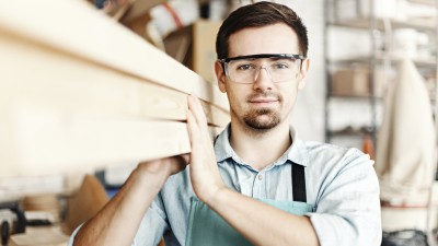 Ist eine Berufsunfähigkeitsversicherung sinnvoll?: Schreiner trägt Holzbalken